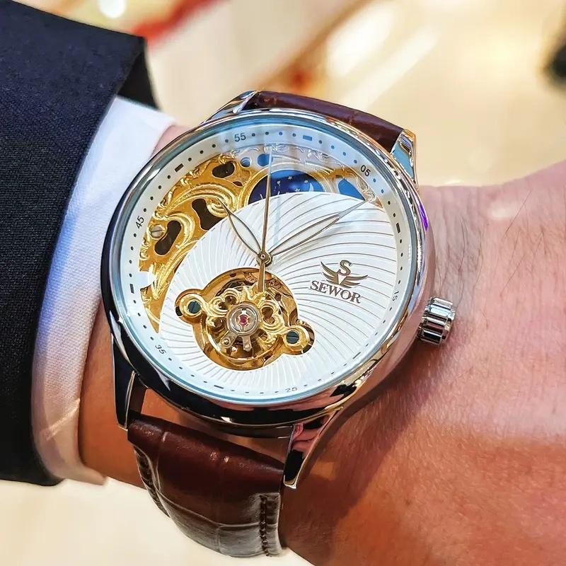 Luxury Watch Makes - นาฬิกาข้อมืออัตโนมัติสำหรับผู้ชายสุดหรู ดีไซน์โครงกระดูก ผสมผสานความสง่างามและความทันสมัย นาฬิกาข้อมือนี้โดดเด่นด้วยดีไซน์โครงกระดูกทูร์บิญองและดีไซน์รูปพระจันทร์ครึ่งเสี้ยว ทำให้เป็นของขวัญในอุดมคติในช่วงวันหยุดและงานสังสรรค์ทางธุรกิจ แสดงให้เห็นถึงความสวยงามแบบย้อนยุคแต่ก็ทันสมัยในสไตล์ธุรกิจ